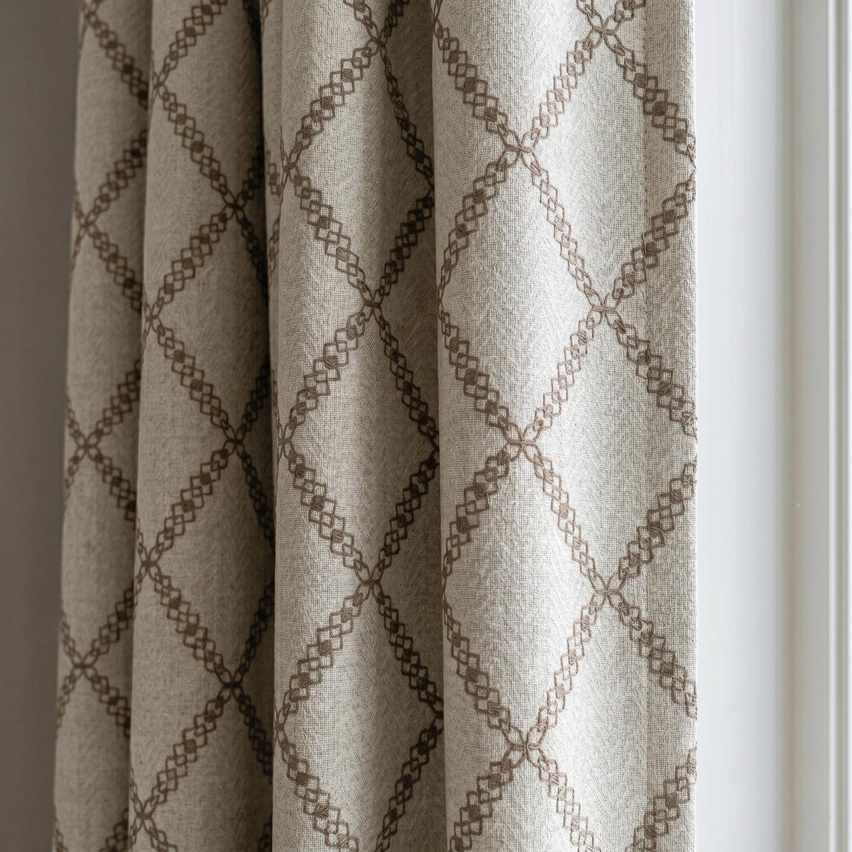 Oatmeal linen-look curtains with brown trellis chain embroidery.