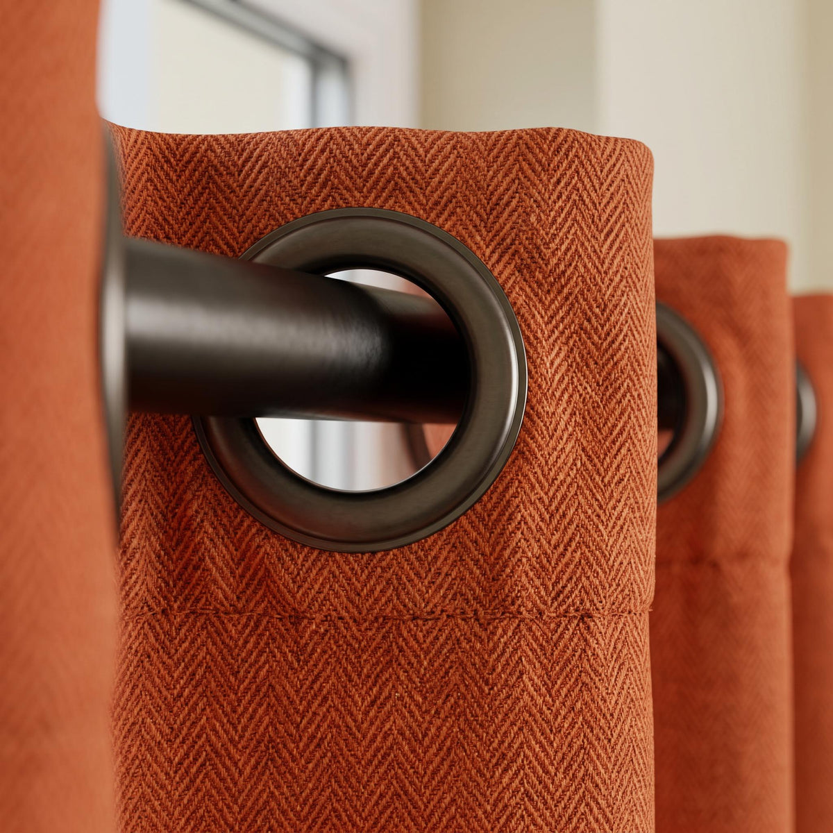 Burnt orange curtain fabric with a subtle woven herringbone texture.