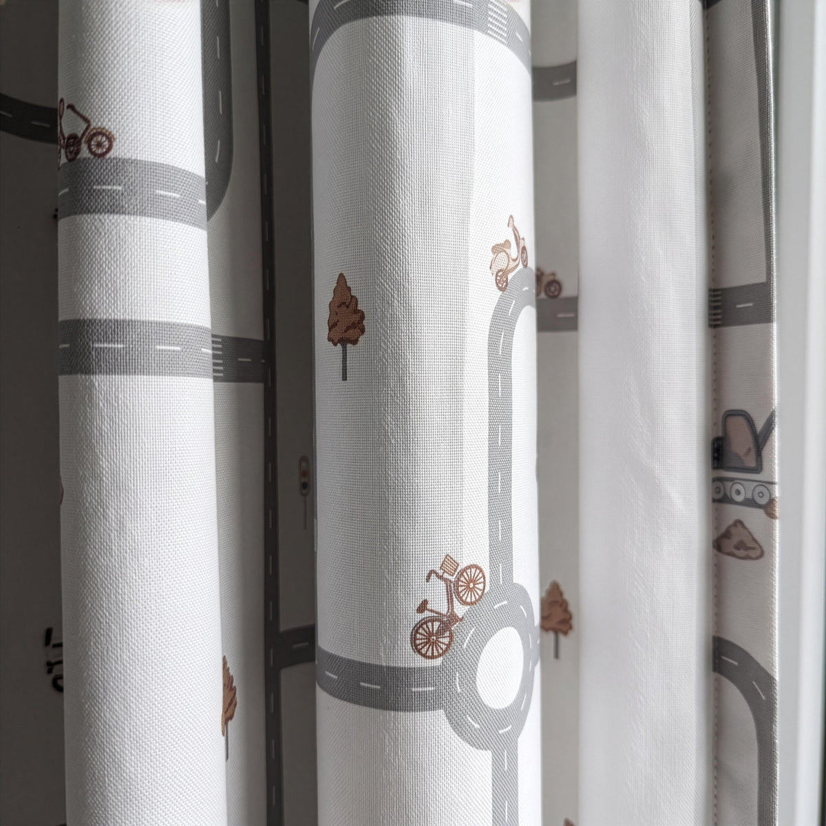 Children's curtain fabric with winding roads, traffic lights and construction vehicles.