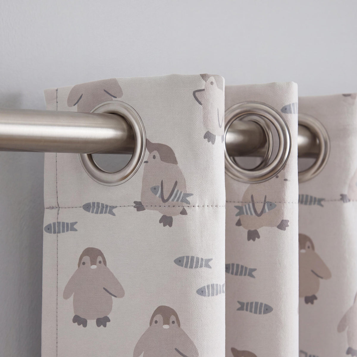 Nursery curtain fabric with penguins and small striped fish in muted colors.